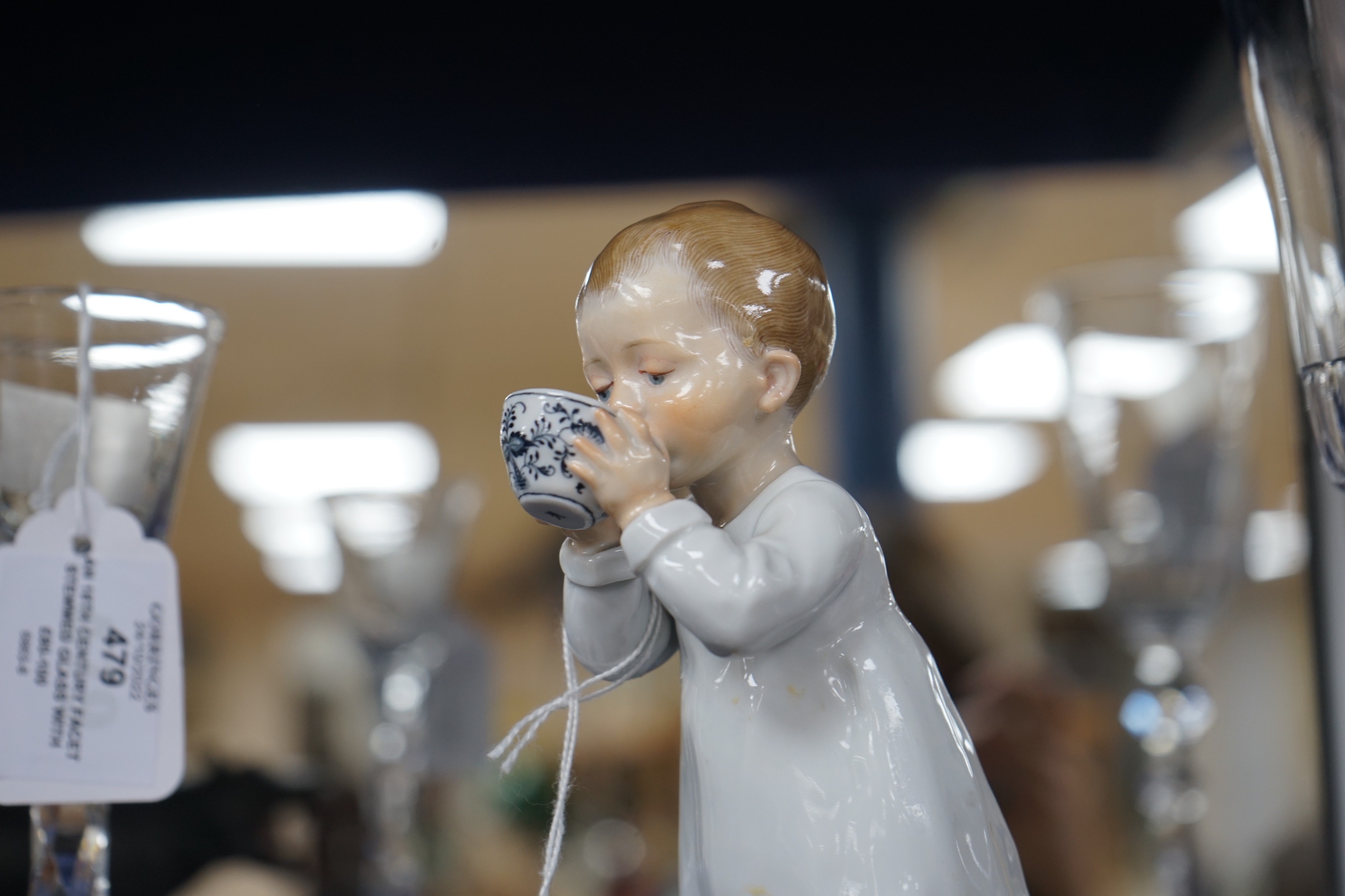 A Meissen figure of a child drinking from a bowl, modelled by Konrad Hentschel, c.1905-1924, 16cm high, faults